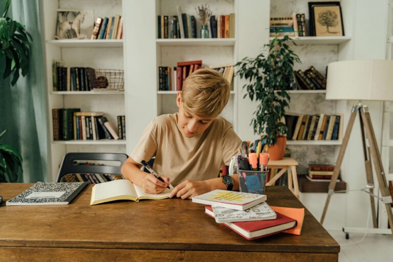 "Image: A child sits at a desk, pen in hand, engaged in journal writing. The journal is open, revealing colorful pages with 'journaling prompts' printed on them. The child appears focused and thoughtful as they explore the prompts, fostering creativity and self-reflection."