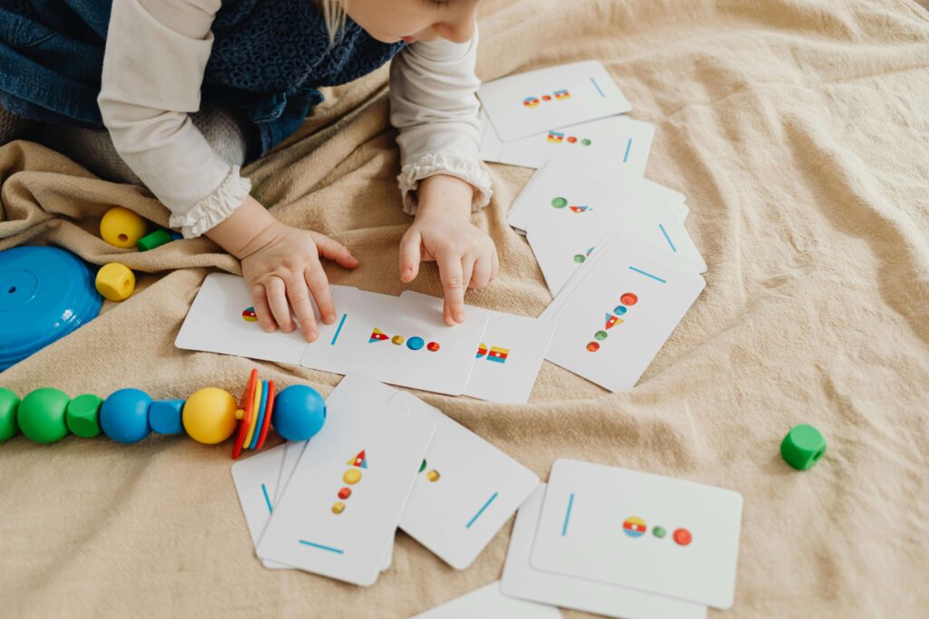 An image of a child playing cards. It is one of the best DIY puzzles for children's brain boosting.  