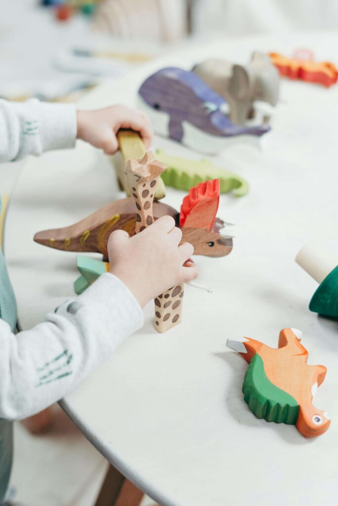 An image of hands of a child playing with animal toys that is good for fine motor skills.