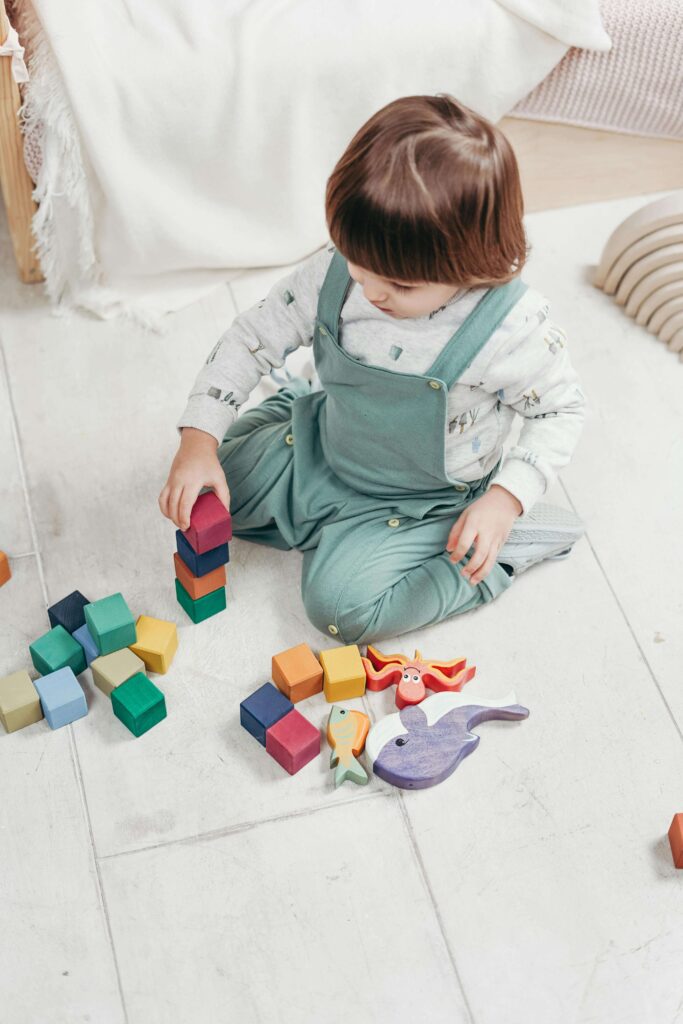 An image of a child trying to stacks blocks, it helps building fine motor skills.