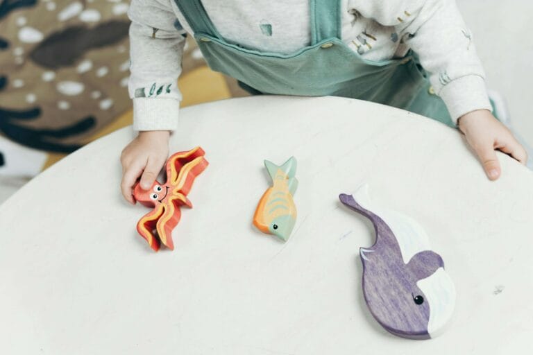 An image of a child playing with sea creature wooden toys. These can be best gifts to enhance the curiosity of marine life and aquariums in a child.