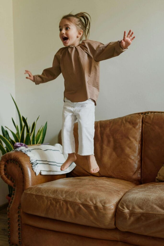 An image of an adhd child who is jumping on the sofa and have no patience to sit still.