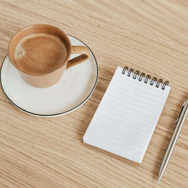 An image of a cute planner with a cup of coffee and a pen is placed on a coffee table.